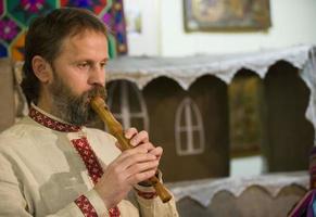 Belarusian national holiday. Slavic man plays an ethnic pipe. Belarusian musician in national clothes. photo