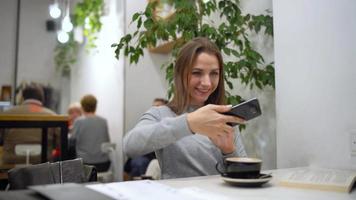 hermosa mujer gasta su hora en un café leyendo un libro, hablando en el teléfono y Bebiendo café video