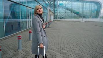 Loiras menina rolos uma mala de viagem perto a aeroporto terminal video