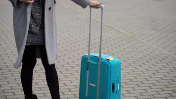 Loiras menina rolos uma mala de viagem perto a aeroporto terminal video