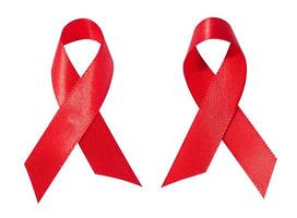 A silk red ribbon in the form of a bow is isolated on a white background, a symbol of the fight against AIDS and a sign of solidarity and support. photo