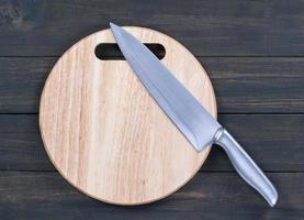 Kitchen knife on wooden round cutting board close up photo