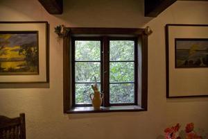 de madera ventana con vista a el verdor con un arcilla jarra con cepillos en el antepecho foto