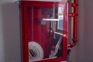 Indoor hydrant box with white hose, nozzle and valve on the office area. The photo is suitable to use for industry background and fire fighter content media.