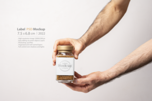 Male hand holding an instant coffee glass jar with blank label isolated on gray background psd