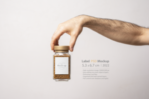 A male hand holding an instant coffee glass jar with blank label psd