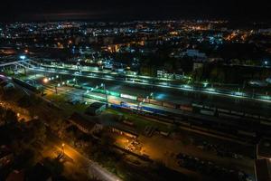 night aerial view over long railway freight trains with lots of wagons stand on parking photo