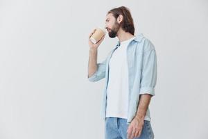 Freelance Millennial man with beard drinking coffee from a crab cup in stylish hipster clothes on a white background photo