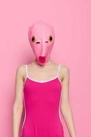 Crazy woman in pink fish head costume poses on pink studio background, provocative Halloween costume photo