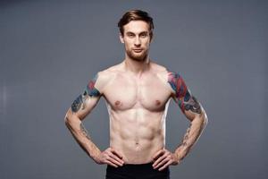 athletic man with pumped up abs tattoos on his arms photo