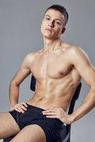 handsome guy resting on a chair with a pumped-up body fitness gym photo