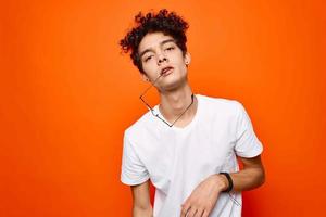 cute guy with curly hair in a white t-shirt gestures with his hands photo