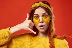 pretty woman wearing yellow glasses hippie fashion red background photo