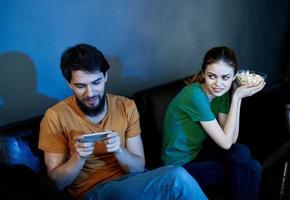 Man and woman on leather couch with popcorn watching TV in the evening photo