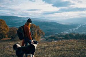 woman with backpack on nature next to dog walk mountain landscape photo