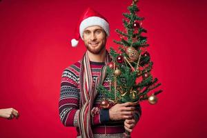 man with decorated christmas tree holiday christmas fun red background photo