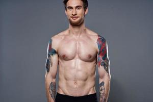 sporty man with a naked torso pumped up press tattoos on his arms photo