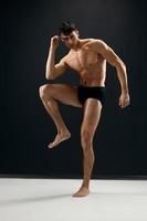 man with a muscular body in black shorts posing dark background photo