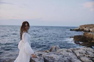 mujer con mojado pelo en blanco vestir posando por el Oceano inalterado foto