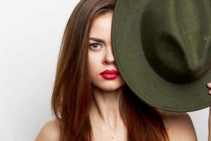 Woman holding hat covers his face bare shoulders near face red lips photo