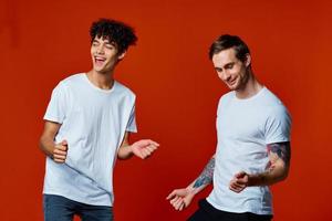 Two cheerful friends in white t-shirts stand side by side isolated background photo