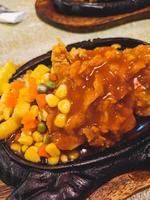 Chicken steak with corn topping served on hot iron plate photo