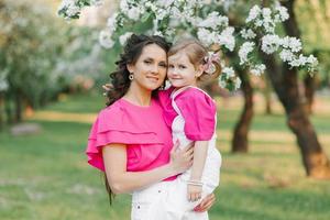 A young beautiful mother is happy and holding her daughter in her arms, who is smiling photo