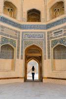 Bukhara, Uzbekistan. March 2022. The girl stands with her back in the doorway of the Kalyan Minaret photo