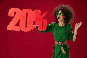 Positive young woman green dress afro hairstyle dark glasses twenty percent in hands studio model unaltered photo