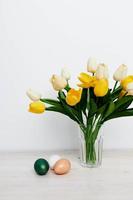 Easter eggs on the table and yellow tulips in a vase Copy Space photo