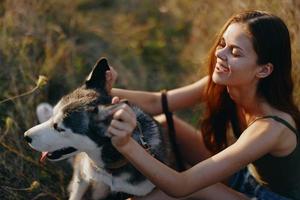 Woman sitting in field with dachshund dog smiling while spending time outdoors with dog friend photo