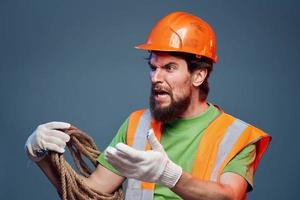 Man in work uniform orange paint rope in hands hard work cropped view photo