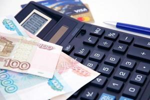 Ruble banknotes, calculator, pen and blurred credit cards close-up. Save money concept photo