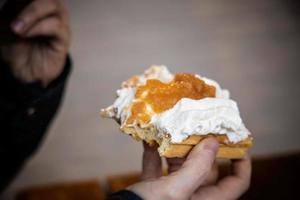 fresh sweet waffle with whipped cream and fruit held in a lung photo