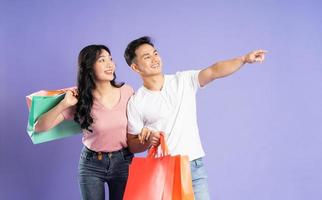 image of asian couple holding shopping bags on purple background photo