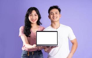 image of asian couple using laptop, isolated on purple background photo