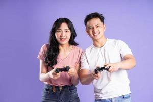image of asian couple playing games, isolated on purple background photo