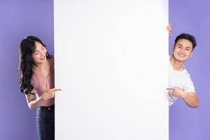 image of asian couple posing next to billboard, isolated on purple background photo