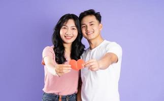 image of asian couple holding a heart sticker, isolated on purple background photo