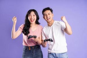 image of asian couple playing games, isolated on purple background photo