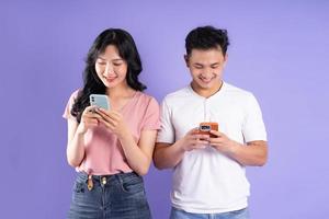 image of asian couple holding smartphone, isolated on purple background photo