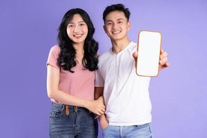 image of asian couple holding smartphone, isolated on purple background photo