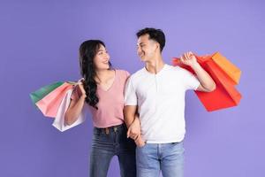 image of asian couple holding shopping bags on purple background photo