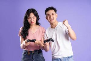 image of asian couple playing games, isolated on purple background photo