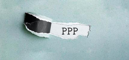 The text ppp loan appearing behind torn green paper photo