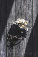 Bunch of wildflowers on gray wooden background in sunlight photo