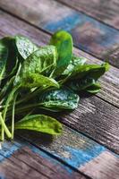 spinach leaves on textured old wood planks, vertical closeup photo