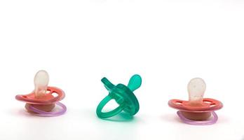 Two pink pacifiers and one turquoise pacifier for newborn on white isolated background. Background. For text. Photo in high quality