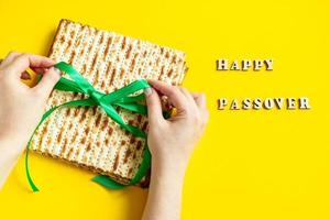 Woman is holding matzah. Celebrating the traditional Jewish holiday of Passover or Pesach. Matzo on a yellow background. photo