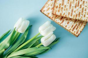 Matzo and white tulips on a blue background. Religious Jewish holiday Pesach. Happy Passover concept. photo